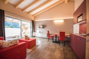a kitchen with a table and red chairs in a room at Alpenblick Nr 8 in Campo Tures