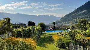 a garden with a pool and mountains in the background at Fröhlichhof Wohnung Apfelblüte in Lagundo