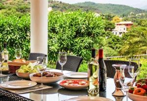 a table with food and wine bottles and wine glasses at Villa Domus Vesta in Marbella