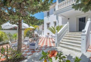 a white house with stairs and chairs and trees at Villa Domus Vesta in Marbella