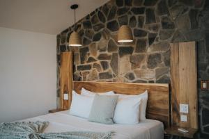 a bedroom with a bed with a stone wall at Cabañas by 7 Valles in Valle de Guadalupe +60 photos