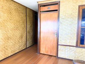 a wooden door in a room with a brick wall at Santai Surf Lodge-Balangan in Uluwatu