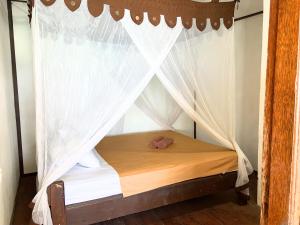 a bedroom with a canopy bed with white curtains at Santai Surf Lodge-Balangan in Uluwatu