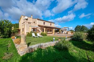 a large stone house with a yard with two chairs at Casa Tolo in Son Servera