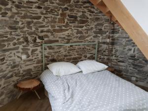 a bed in a room with a stone wall at Gîte Du Moulin De La Violaye in Fay-de-Bretagne