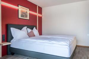 a bedroom with a white bed with a red wall at Aumia Apartment Rubin in Völs am Schlern