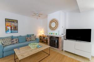 a living room with a blue couch and a flat screen tv at Villa Diani in Binibeca