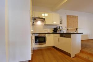 a kitchen with white cabinets and a wooden floor at Panorama Chalet in Mittersill +4 photos