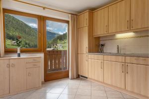 a kitchen with wooden cabinets and a large window at Ferienhaus Berger in Sarntal