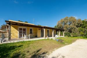 a small yellow house with a dirt road in front of it at Casa Vacanza Ghisu in SantʼAnna Arresi