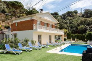 a villa with a swimming pool and lounge chairs at Ainara Luxury in Lloret de Mar