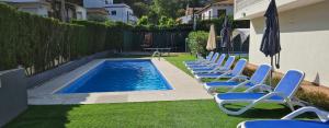 a row of lawn chairs next to a swimming pool at Ainara Luxury in Lloret de Mar