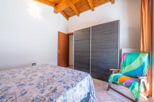 a bedroom with a bed and a colorful chair at Casa Vacanza Ghisu in SantʼAnna Arresi