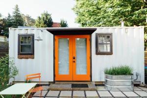 a tiny house with an orange door on a patio at EBENEZER Cottage in Discovery Bay