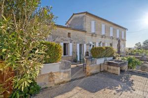 an old stone house with bushes in front of it at Chambre d'Hotes La Roseraie in Saint-Émilion