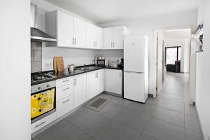 a kitchen with white cabinets and a white refrigerator at Casa Caminho da Esperança in Porto Judeu