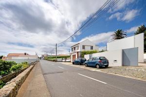a house with two cars parked on the side of a street at Casa Caminho da Esperança in Porto Judeu