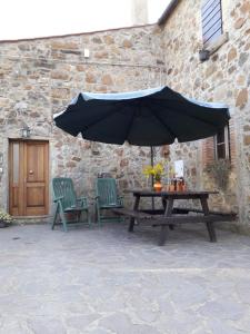 a picnic table and two chairs with an umbrella at Querciagrossa da Dora in Roccastrada