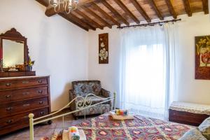 a bedroom with a bed and a chair and a window at Querciagrossa da Dora in Roccastrada