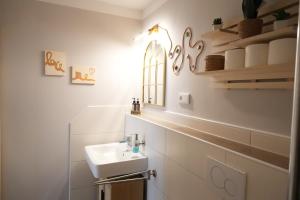 a white bathroom with a sink and a mirror at Haevn Erholung, Feuer, Wasser, Luft in Reußenköge +47 photos