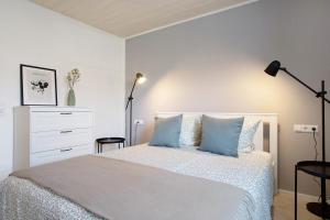 a white bedroom with a bed with blue pillows at Karlotta in Eriskirch