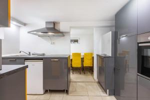 a kitchen with stainless steel appliances and yellow chairs at Living the Green in Friedrichsdorf