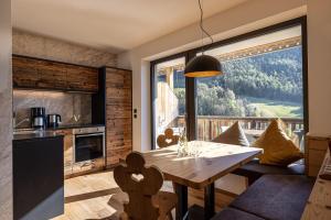 a kitchen and dining room with a table and a large window at Sonnleiten Sonnenadler 4 in Collepietra