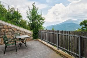 a table and chair on a patio with mountains in the background at Haus Pferscher in Barbiano