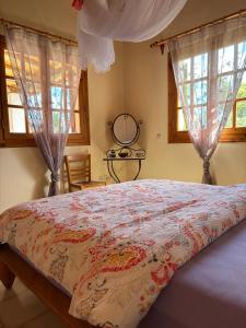 a bed in a bedroom with windows and a bedspread at Divas Gartenhaus in Vasilítsion
