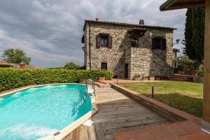 an outdoor swimming pool in front of a stone house at La Petrosa in Radda in Chianti