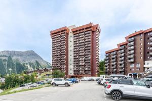 a parking lot with cars parked in front of tall buildings at Studio Avec Vue Splendide in Villarembert