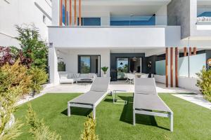 an exterior view of a house with white chairs and grass at Ground floor 2bed Miradores del Sol in Estepona