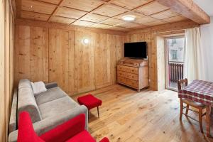 a living room with a couch and a television at Casa Patty Moena in Moena