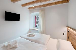 a white bedroom with a bed with a flat screen tv at Casa Patty Moena in Moena