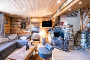 a living room with a stone fireplace in a log cabin at Chalet Vardasse in Manigod
