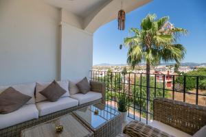 a balcony with a couch and a palm tree at Marbella Beach San Pedro in Marbella