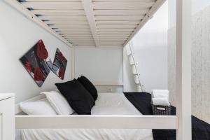 a white bed with black pillows in a white room at Apartamento La Listada Bajo in La Listada