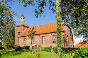 una vecchia chiesa di mattoni con una torre e un campanile di Ferienhaus Berdum a Wittmund