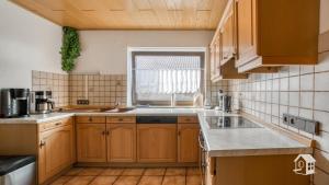 a kitchen with wooden cabinets and a window at Ferienhaus Mengelberg in Roschbach