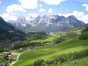 a green valley with mountains in the background with a village at Ferienhaus Amrhein in Siegsdorf