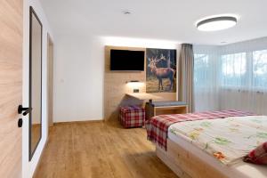 ein Schlafzimmer mit Bett, Schreibtisch und Fernseher in der Unterkunft Kaiserchalet in Höchenschwand