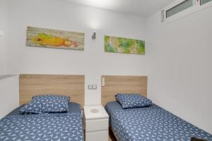two beds in a small room with blue sheets at El Nido de los Ángeles in Playa del Ingles +106 photos