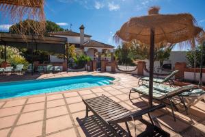 a pool with two chairs and an umbrella at Villa Minerva in Ronda