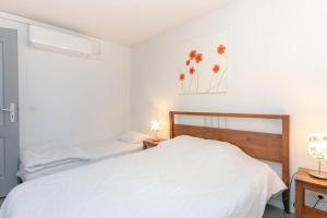 a white bedroom with two beds and two lamps at Appartement Aix Les Bains in Aix-les-Bains