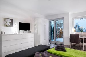a white living room with a television and a table at Schwarzwaldblick C App 2 mit Pool in Schönwald