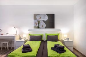 a bedroom with a bed with green sheets and a desk at Schwarzwaldblick C App 2 mit Pool in Schönwald +16 photos