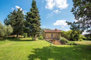 an old stone house in a field with trees at Villa Agriturismo Il Pratone in Castiglione dʼOrcia