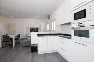 a kitchen with white cabinets and a table with chairs at Apartamento Marei 2 in Cala Blanca