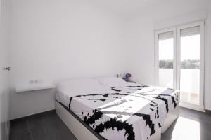 a white bedroom with a black and white blanket on a bed at Apartamento Marei 2 in Cala Blanca +28 photos