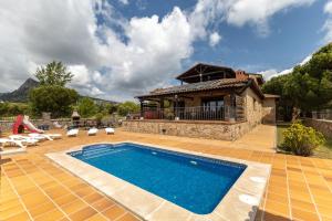 a villa with a swimming pool in front of a house at Sierra Norte Madrid in El Berrueco